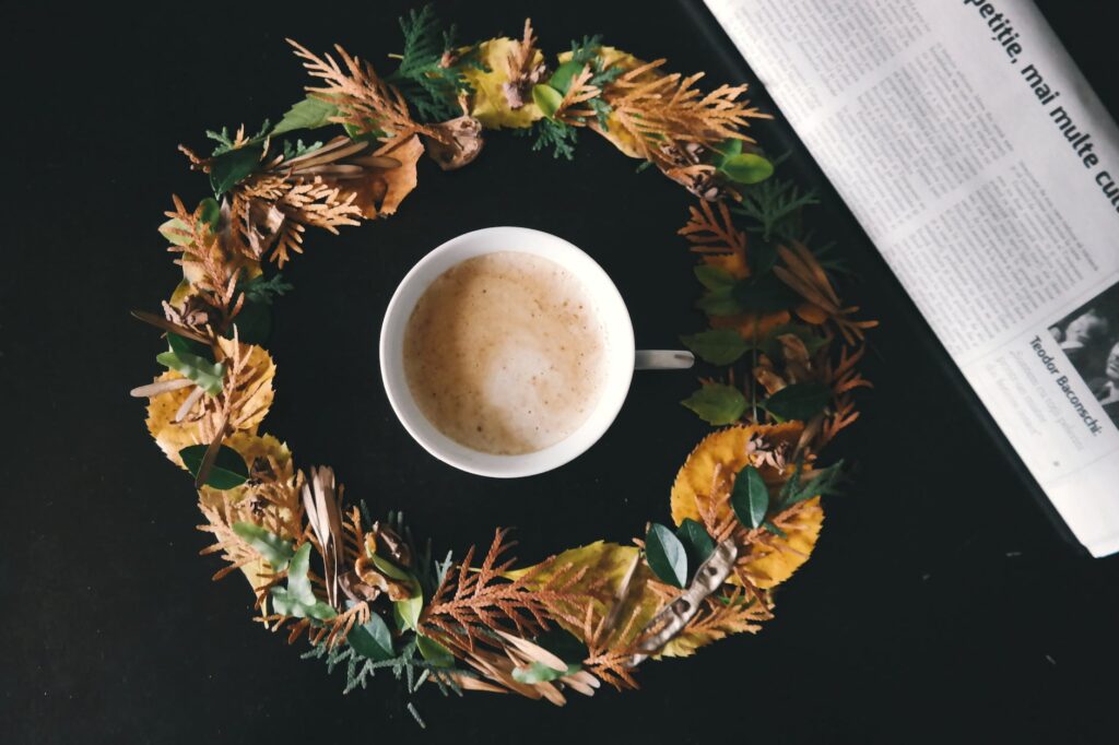 white cup of coffee in the middle of yellow and green flower wreath